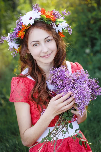 Beautiful woman with a wreath and with a bouquet of lilacs — Stock Photo, Image
