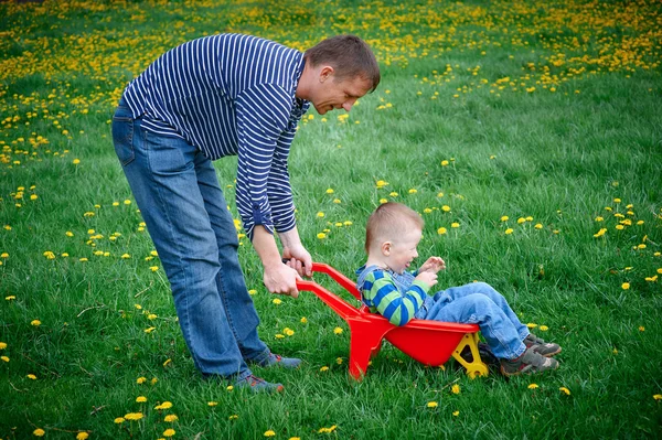 Vader rollen zijn zoon in een kruiwagen — Stockfoto