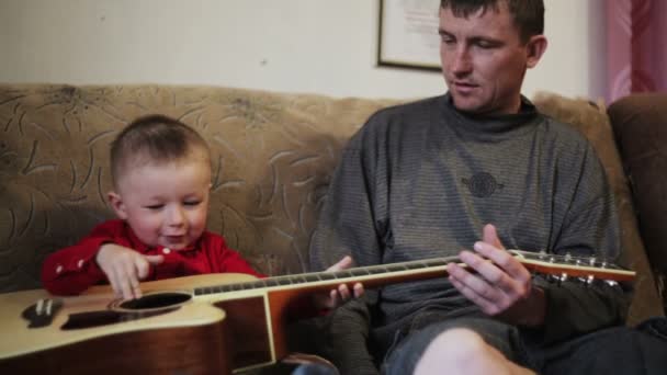 年轻的父亲教他年幼的儿子弹吉他 — 图库视频影像