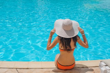 Havuzun kenarında oturan genç güzel kadın