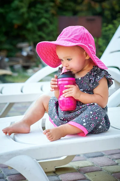 A kislány egy piros kalap, iszik, egy bögre — Stock Fotó