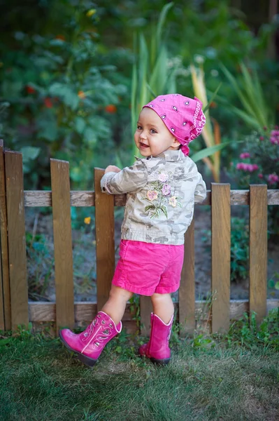 Kleines Mädchen in rosa Schuhen am Zaun — Stockfoto