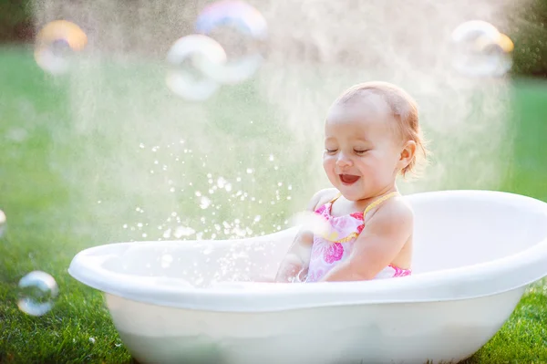 Malá holčička se koupe ve vaně s mýdlové bubliny — Stock fotografie