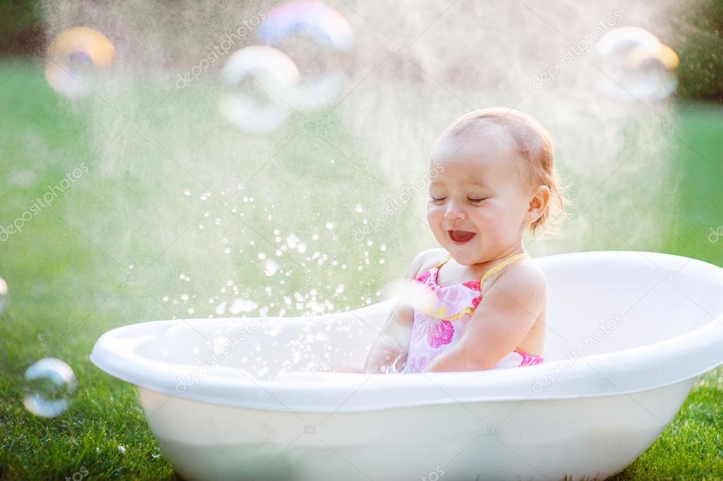 little girl bathes in a bath with soap bubbles