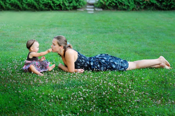 Jovem mãe brincando com sua filha em um prado — Fotografia de Stock