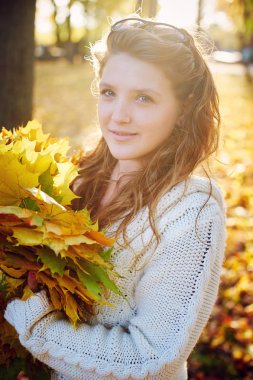 Genç güzel kadın parkta bir çelenk yaprakların yapar