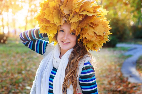 Happy woman in a wreath of yellow leaves walking — Stock Photo, Image