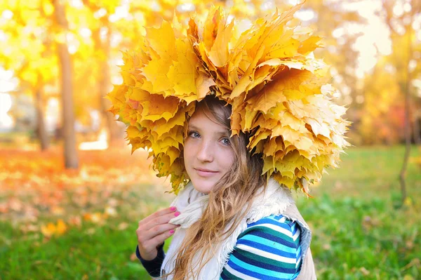 Happy woman in a wreath of yellow leaves walking — Stock Photo, Image