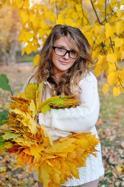 Young pretty woman in park makes a wreath of leaves — Stock Photo, Image