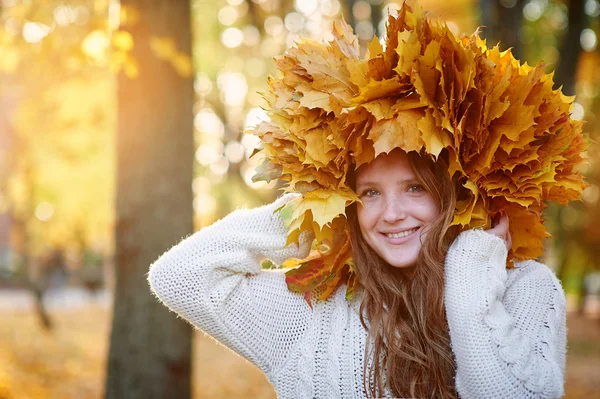 Happy woman in a wreath of yellow leaves walking — Stock Photo, Image
