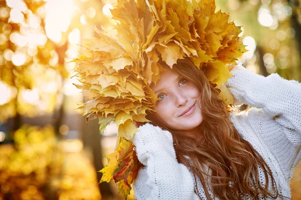 Happy woman in a wreath of yellow leaves walking — Stock Photo, Image