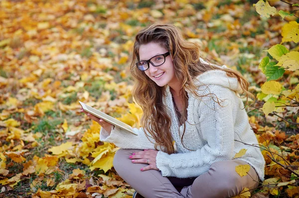 Sonbahar parkta oturan bir tablet ile genç kadın — Stok fotoğraf