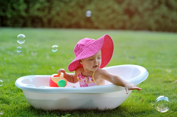 Kleines Mädchen badet in einer Badewanne mit Seifenblasen — Stockfoto