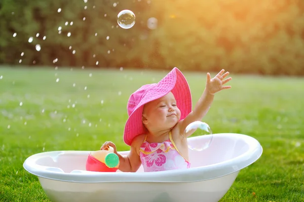 Kleines Mädchen badet in einer Badewanne mit Seifenblasen — Stockfoto