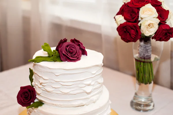 Beau gâteau blanc et bouquet rouge — Photo