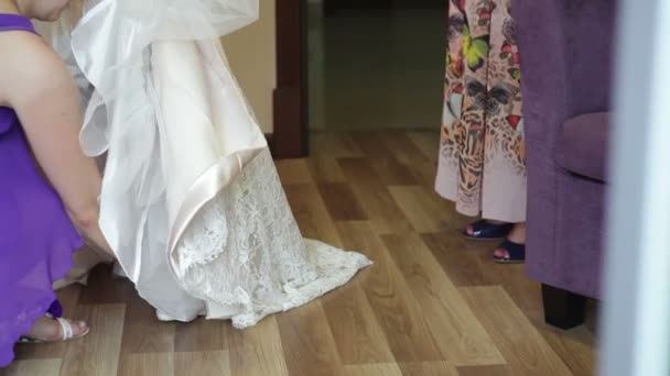 Покоївка нареченої допомагає нареченій носити взуття — стокове відео