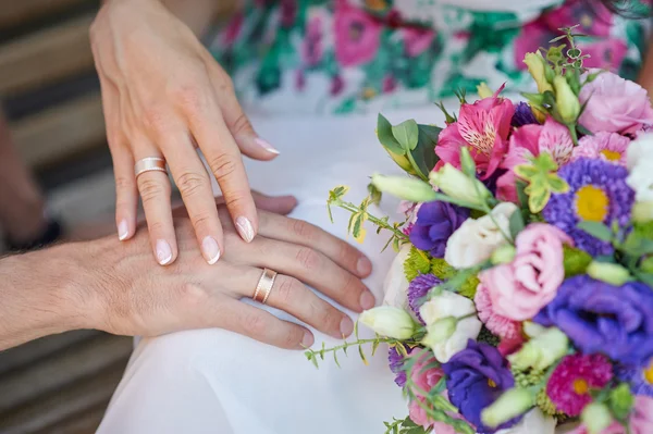 Mani di sposa e sposo con anelli e bouquet da sposa — Foto Stock