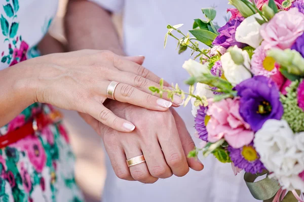 Hands of bride and groom with rings and bouquet — Stock Photo, Image