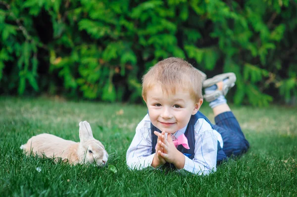 Kleine jongen spelen met konijn op groen gras — Stockfoto