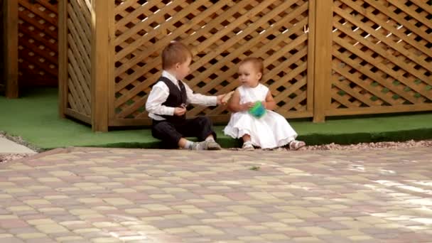 Kleine jongen en meisje zit in de buurt van de gazebo en eten — Stockvideo