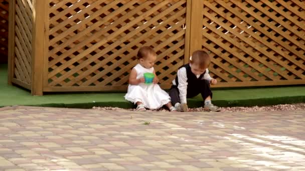 Kleine jongen en meisje zit in de buurt van de gazebo en eten — Stockvideo