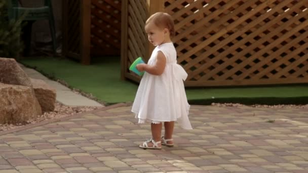Маленькая девочка ходит по детской площадке с ведром — стоковое видео