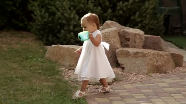 Маленькая девочка ходит по детской площадке с ведром — стоковое видео