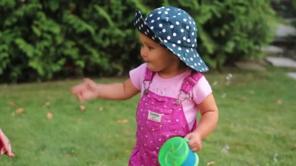 Маленькая девочка играет в саду с мыльными пузырями — стоковое видео