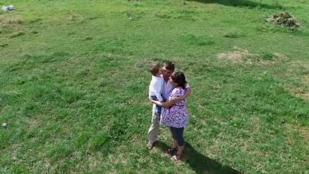 Молода сім'я гуляє на літньому лузі — стокове відео