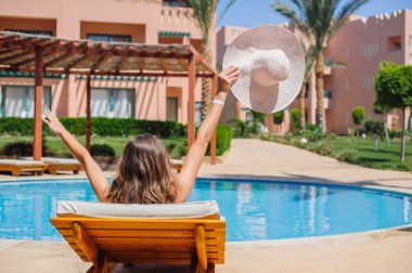 mutlu kadın bir tembel havuz kenarında güneşlenirken