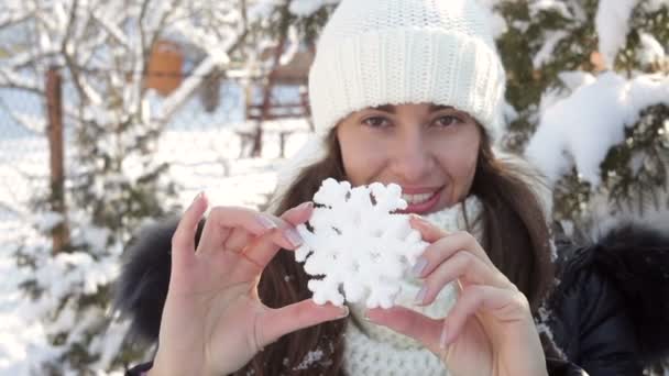 Женщина в зимней шляпе держит большую снежинку — стоковое видео