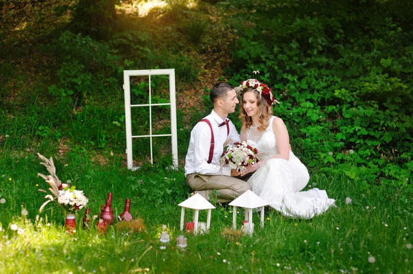 Groom and bride sit on the grass in the park — Stock Photo, Image