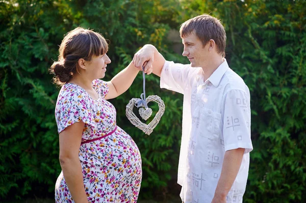 Mulher grávida e seu marido segurando o coração — Fotografia de Stock