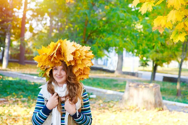 Happy woman in a wreath of yellow leaves walking in autumn park — Stock Photo, Image