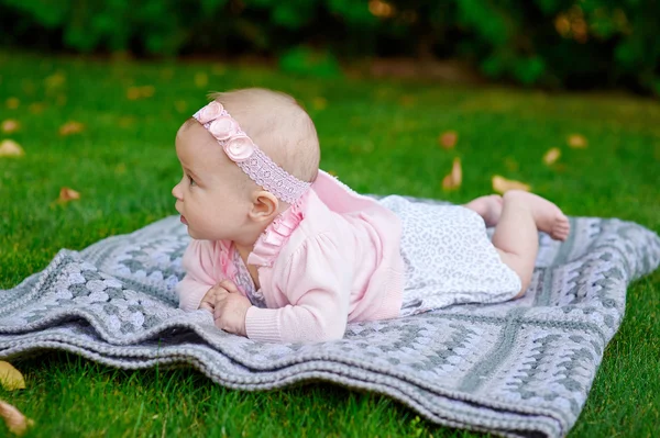 Happy little girl lying on a blanket in the park — Stock Photo, Image