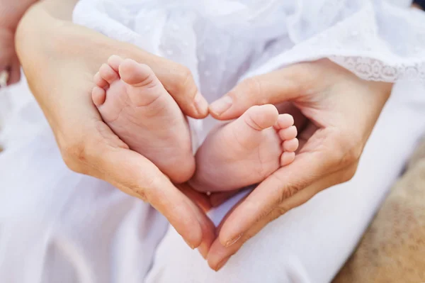 Mother's hands forming a heart among her baby's feet — Stock Photo, Image