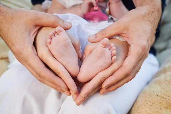 Μαμά και τον μπαμπά να κατέχουν τα πόδια του μωρού με τη μορφή της καρδιάς — Φωτογραφία Αρχείου