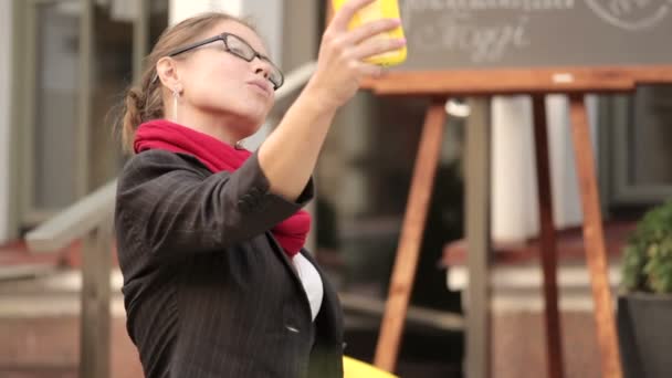 Молодая женщина сидит в кафе и делает селфи — стоковое видео