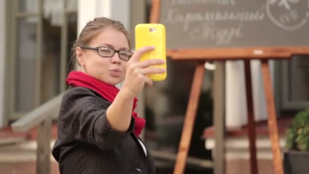 Mujer joven sentada en la cafetería y tomando selfie — Vídeos de Stock