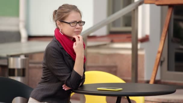 Nő ül egy kávézóban, smartphone piros sállal — Stock videók