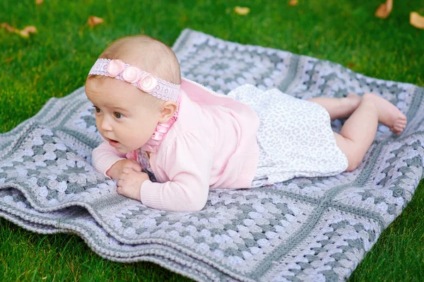 Mooi babymeisje is liggend op een geruite deken — Stockfoto