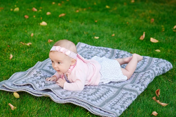 Beautiful little baby girl is lying on a plaid blanket — Stock Photo, Image