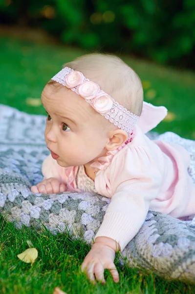 Beautiful little baby girl is lying on a plaid blanket — Stock Photo, Image