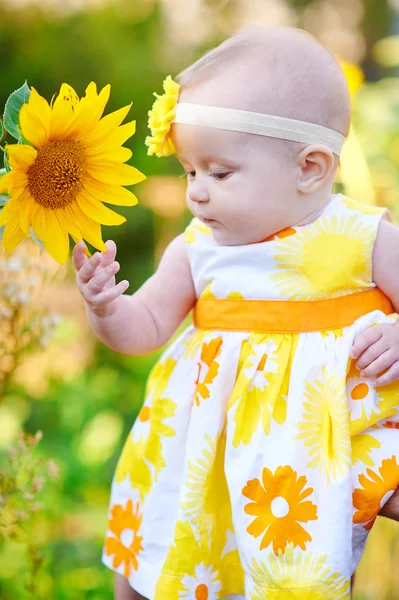 Mooi meisje in een gele jurk ruiken een zonnebloem — Stockfoto