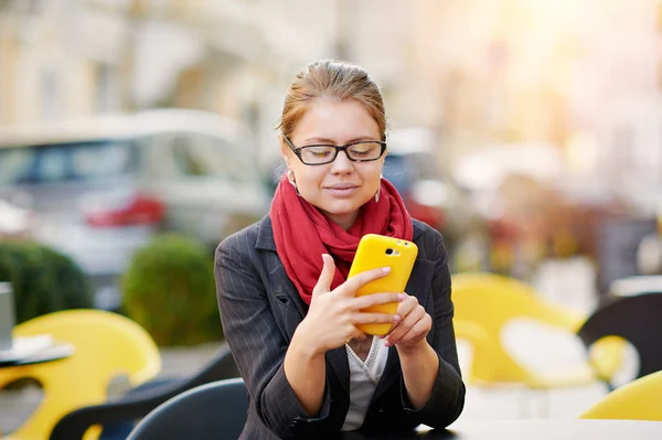 Joven mujer de negocios está utilizando el teléfono inteligente para el trabajo en la cafetería — Foto de Stock
