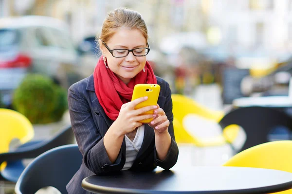 Joven mujer de negocios está utilizando el teléfono inteligente para el trabajo en la cafetería — Foto de Stock