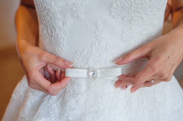 Mains de mariée sur la ceinture avec arc — Photo