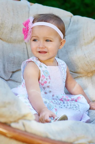 Счастливая маленькая девочка сидит на диване и улыбается — стоковое фото