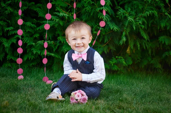Bir arka plan dekorasyon çim üzerinde parkta oturan mutlu küçük çocuk — Stok fotoğraf