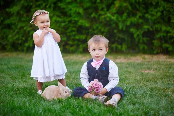 I bambini piccoli con un coniglio coniglio hanno una Pasqua a sfondo erba verde — Foto Stock